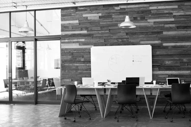 Training room with a whiteboard, work tables and a reclaimed-wood wall